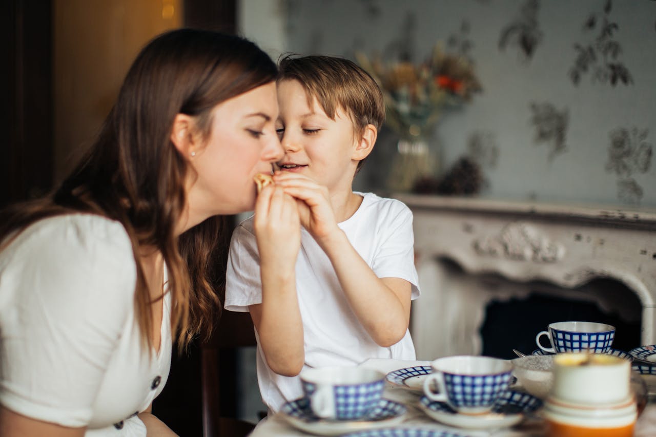 Cozy moment of mother and son enjoying snacks together at a table.